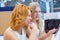 Two young beautiful women in a travel agency choosing a vacation trip, using the interactive screen.