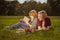 Two young boy studying lesson sitting on green grass in park. Brothers reading book together. Older brother helps younger making