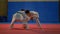 Two young boys dressed in white karate kimonos playing with a glove at the dojo