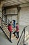 Two young builders in workwear standing on staircase inside unfinished building