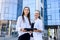 Two young business ladies posing outside office building. Women and business