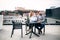 Two young business people with laptop sitting on a terrace outside office, working.