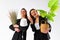 Two young business woman dressed black suit smile holding houseplant and lamp standing isolated on white background. Moving