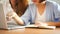 Two young business women sitting at table in cafe. Asian women using laptop and cup of coffee.