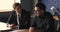 Two young businessmen chatting sit at desk in office