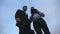 Two young businessmen meet, shake hands and talking outdoor. Business men using tablet pc outside with sky at background