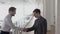 Two young businessmen shaking hands in office gallery, slow motion.