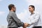 Two young businessmen shaking hands over a deal