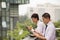 Two young businessmen working and eating outdoors over lunch break