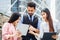 Two young businessmen and a young secretary are looking at business information on a tablet.