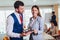 Two young businesspeople using digital tablet while colleague in background. Selective focus