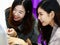 Two young businesswomen colleagues in working office style clothes looking at desktop computer screen together and express