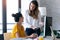 Two young businesswomen talking and reviewing they last work in the digital tablet in the office