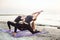 Two young caucasian females practicing yoga on beach