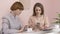 Two young Caucasian girls sitting in a cafe and smiling, using a smartphone, texting, typing. The girls are in a cafe