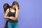 Two young caucasian women with dark hair stand embracing, one besides another one with face palm, strong emotions.