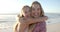 Two young Caucasian women embrace joyfully on a sunny beach