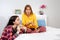 Two young Caucasian women are relaxing in the bedroom, chatting and appraising something on their smartphone. Concept of LGBT