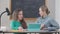 Two young Caucasian women sitting at desk in classroom talking studying in university. Portrait of little person and