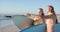 Two young Caucasian women stand on a sunny beach, with copy space