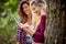 Two young cheerful pretty girls looking at mobile phone and laughing. Summertime, mountain landscape. Freedom, friendship, nature