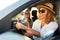 Two young cheerful smiling women in a car on vacation trip to the sea beach. Girl in glasses driving a vehicle from