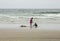 Two young children, a boy and a girl, playing in the sand and water at the beach