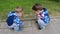 Two young children, boys sit on the sidewalk in the summer and consider the life of insects, ants, the concept of children`s