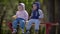 Two young children eating bananas sitting on the bench