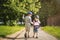 Two young children friends boy and girl hold hands and walk along road in summer green park on sunny afternoon. Child friendship