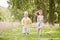 Two young children running on path smiling