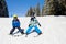 Two young children, siblings brothers, skiing in Austrian mountains on a sunny day