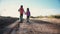 Two young children walking along a dirt road