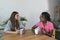 Two young colleagues at a web developing company a black and a white woman sitting down for a coffee break and talk