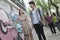 Two young couples walking down the street by a wall with graffiti, smiling and flirting with each other