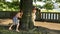 Two young cute teen girls play indulge in the Park, run around the tree.