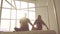 Two young fair-skinned women practicing yoga sitting on soft surface