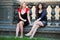 Two young fashion beautiful women sitting on balustrade