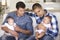 Two Young Fathers On Sofa At Home