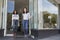 Two young female coffee shop owners stand outside their shop