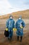 Two young female researchers in protective workwear standing on polluted soil
