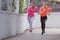 Two Young female runners in hoody  jogging in the city street.Fit body requires hard work. Urban sport concept. Two Young females