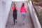 Two Young female runners in hoody  jogging in the city street.Fit body requires hard work. Urban sport concept. Two Young females