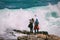 Two young female tourists facing and photographing a huge dangerous wave