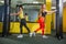 Two young fitness woman execute exercise with exercise-machine Cable Crossover in gym, horizontal photo.