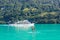 Two young girl friends standing on paddleboard on turquoise Lake Brienz in Switzerland. Tourist boat in background. Switzerland