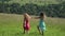 Two young girlfriend running hand in hand on the green meadow