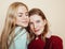 Two young girlfriends in winter sweaters indoors having fun. Lifestyle. Blond teen friends close up