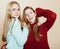 Two young girlfriends in winter sweaters indoors having fun. Lifestyle. Blond teen friends close up