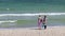 Two young girls in beach swimsuits stand on the sand of the seashore and enjoy a beautiful view of the sea or ocean